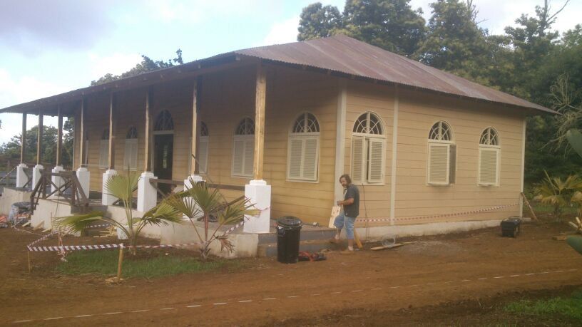 Un hombre está parado frente a una casa de madera.