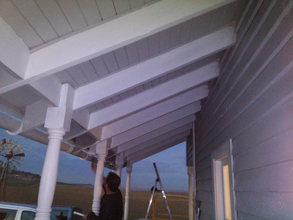 Un hombre está parado debajo de un porche con una escalera.