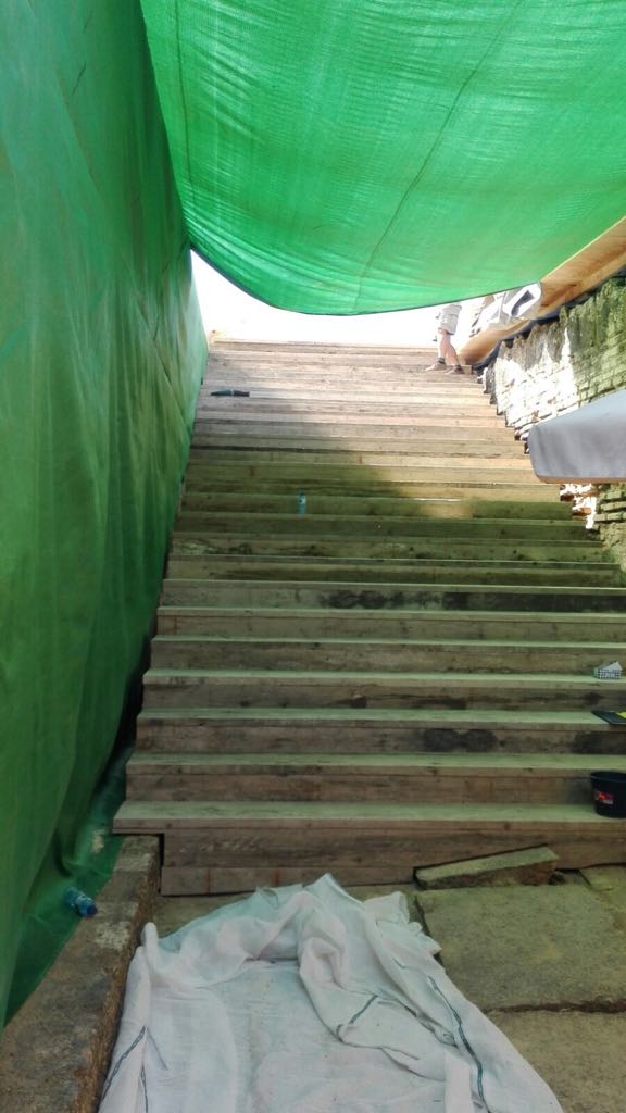 Una persona sube unas escaleras bajo una lona verde.