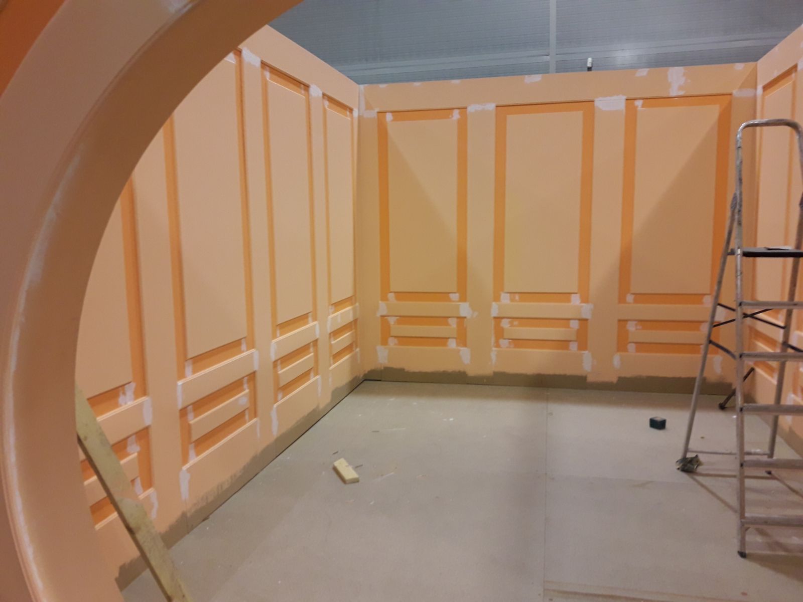 Una habitación con paredes naranjas y una escalera en el suelo.