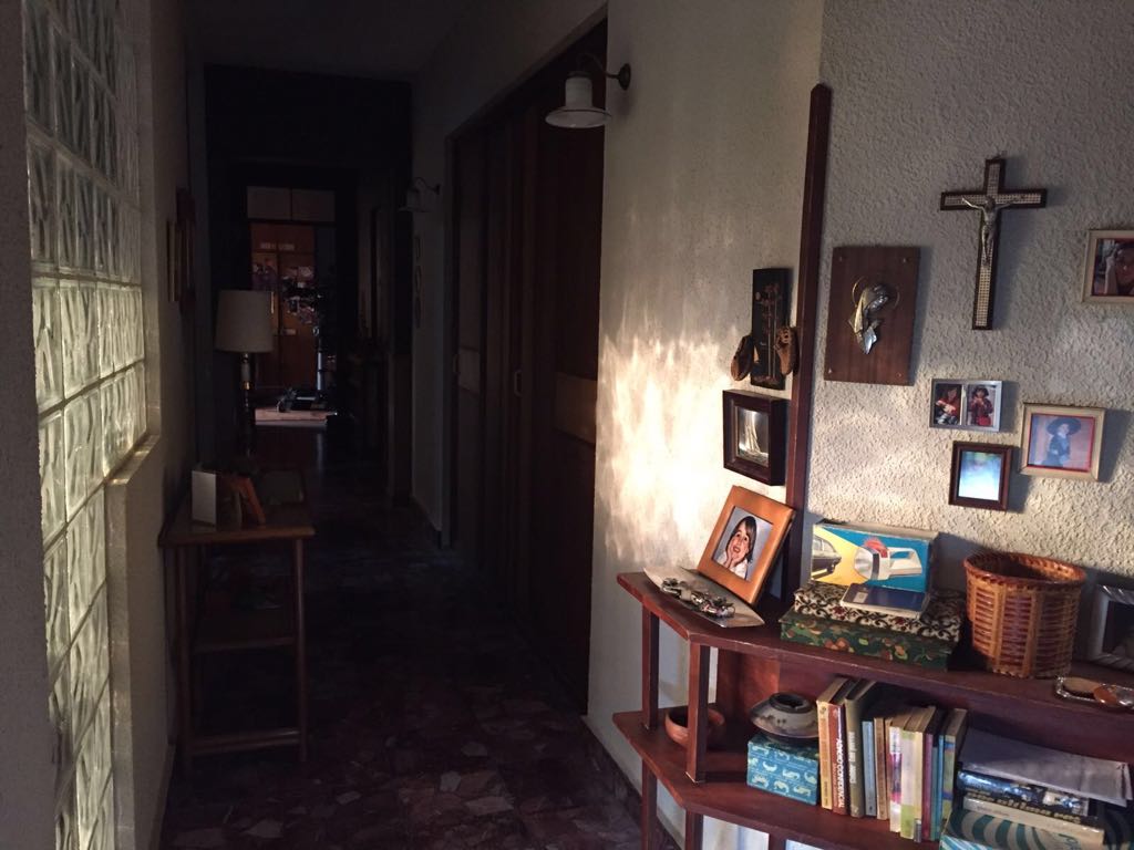 Un pasillo con cuadros en la pared y una cruz en la pared.