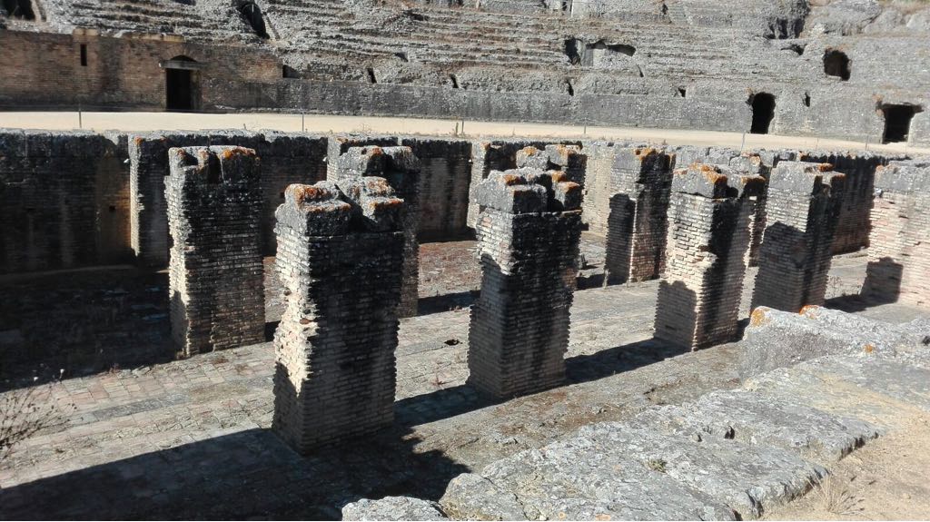 Una hilera de pilares de piedra frente a un edificio de ladrillo