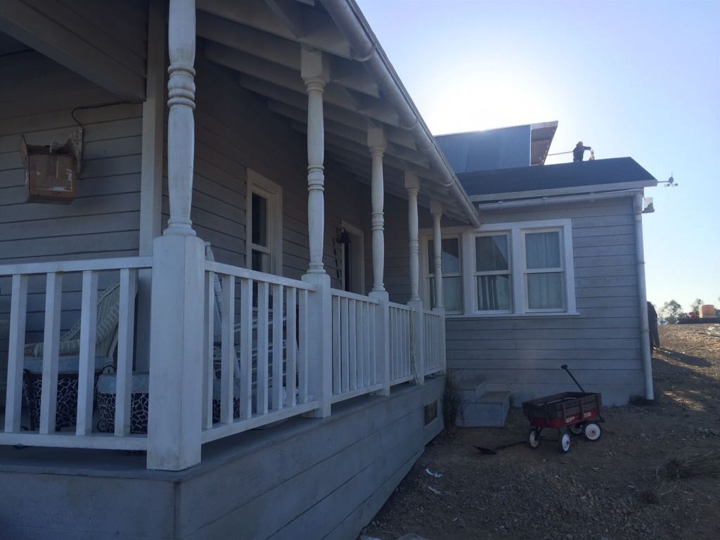 Una casa con un porche y un carro rojo delante de ella.