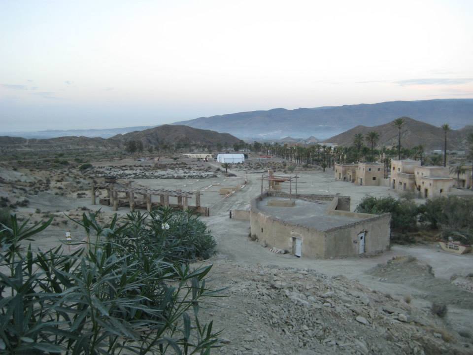 Un paisaje desértico con algunos edificios y montañas al fondo.