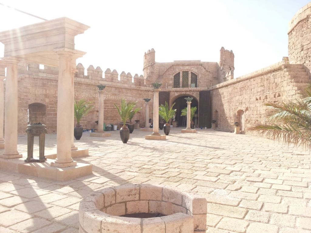 Un patio de ladrillo con columnas y un pozo en el medio.