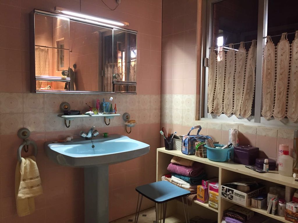 Un baño con lavabo, espejo, estanterías y ventana.