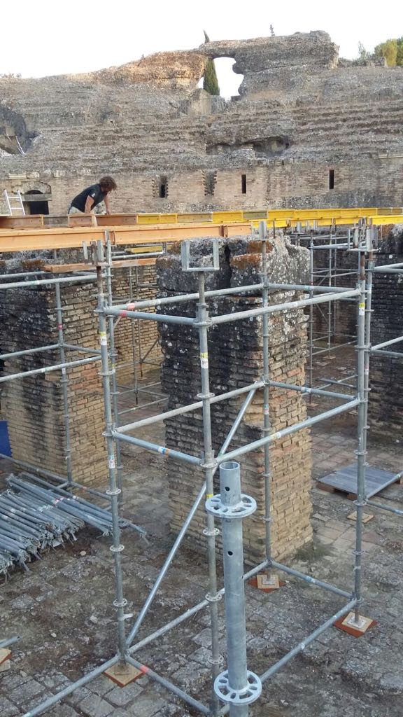 Un hombre está de pie sobre un andamio frente a un edificio en construcción.