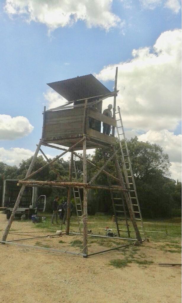 Un hombre está parado en lo alto de una torre de madera.