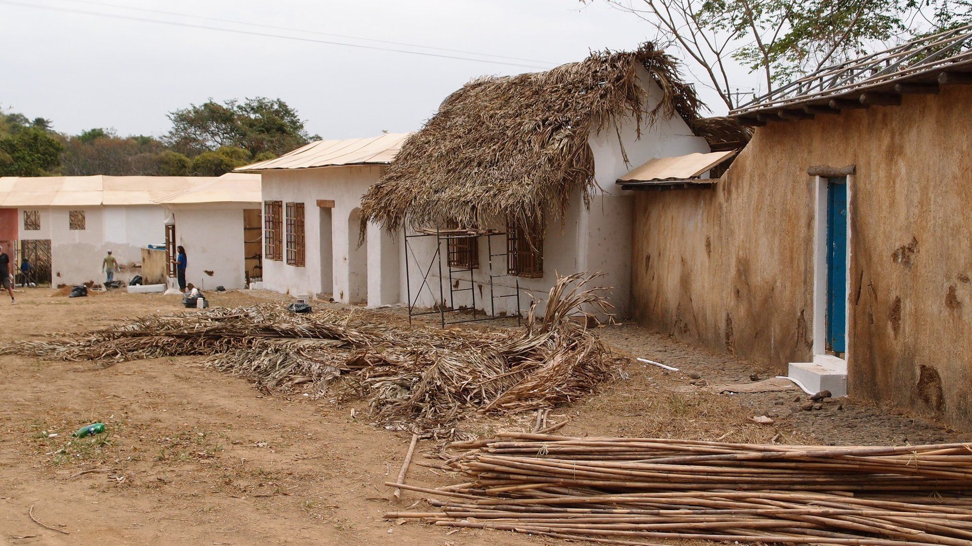 Un edificio con techo de paja está rodeado de otros edificios.