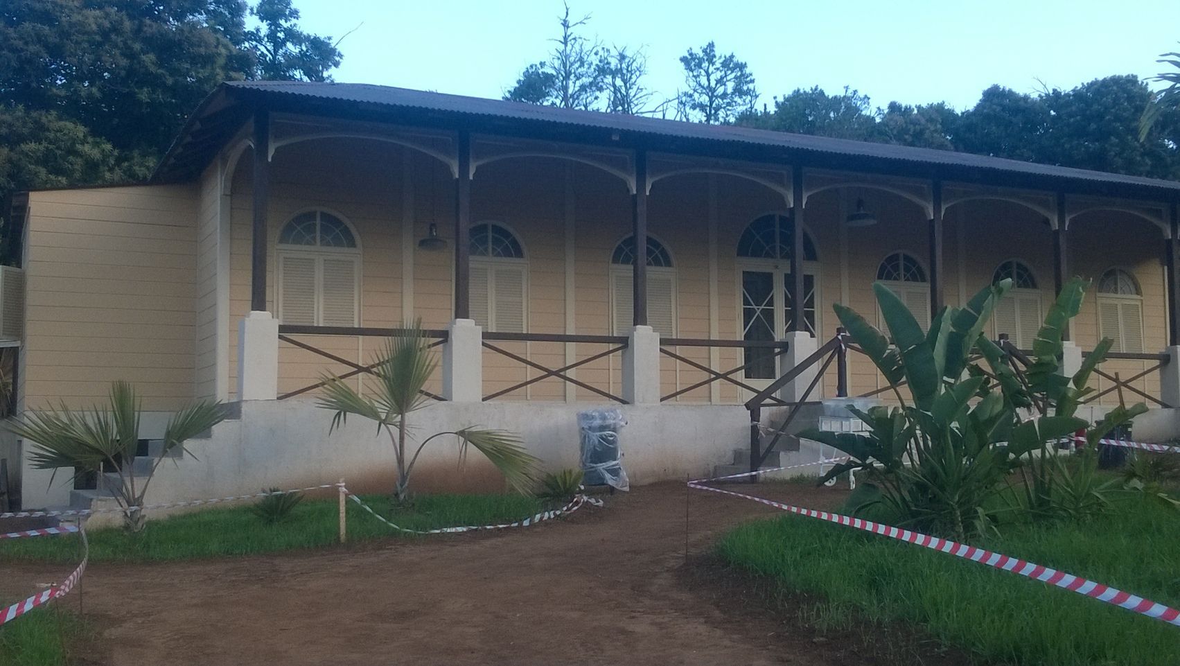 Un gran edificio con porche está rodeado de césped y árboles.
