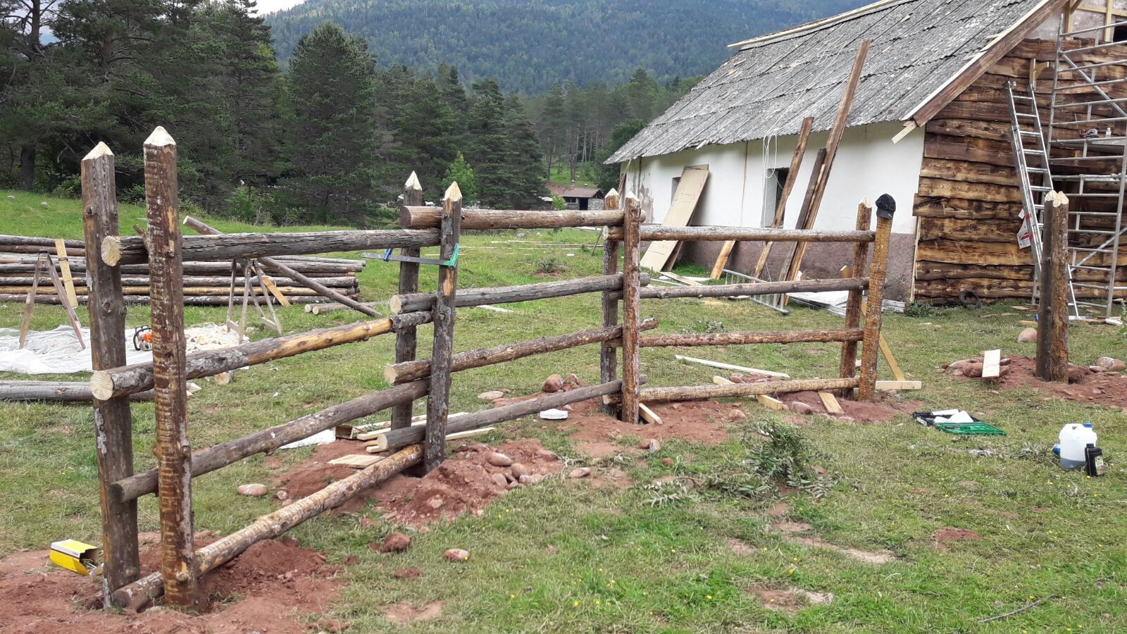 Se está construyendo una valla de madera en un campo delante de una casa.