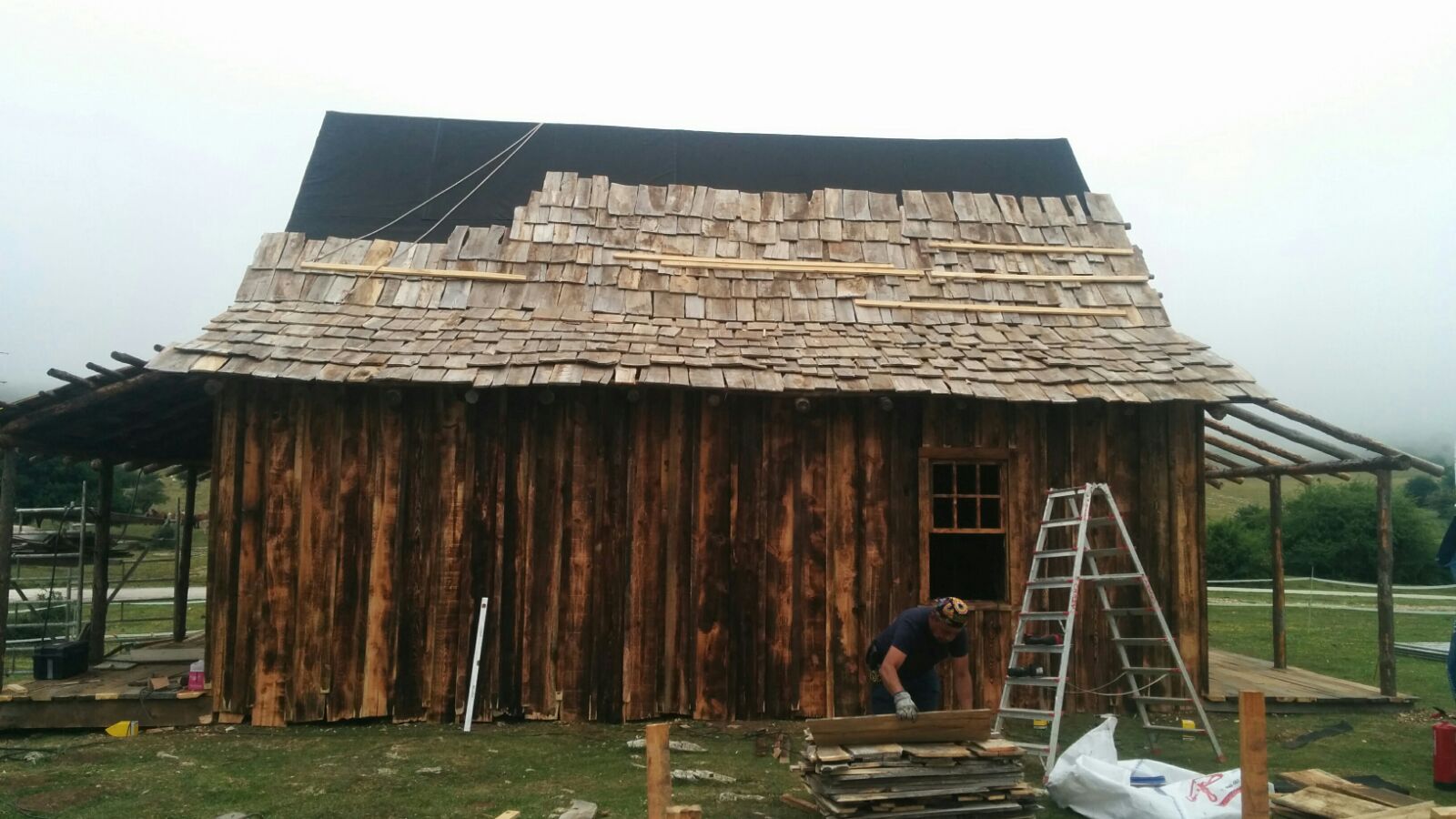 Un hombre está trabajando en el techo de un edificio de madera.