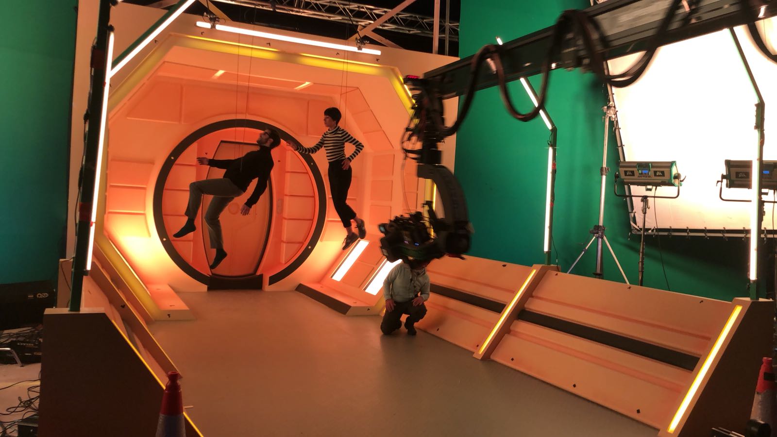 Un hombre y una mujer están parados frente a una pantalla verde en un estudio.