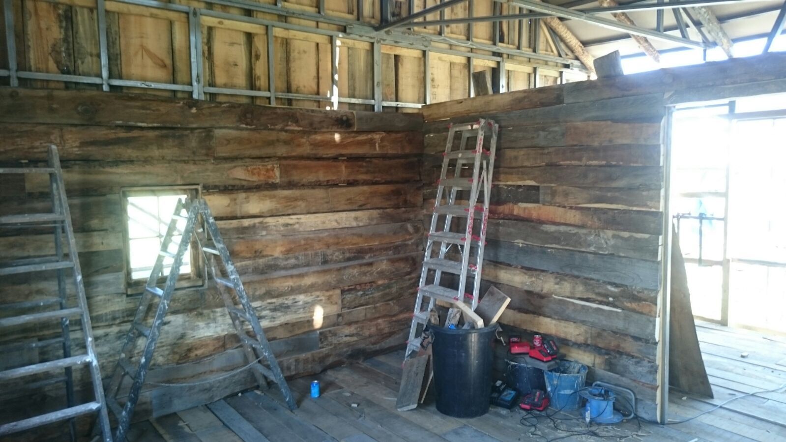Una habitación de madera con una escalera y un cubo en el suelo.
