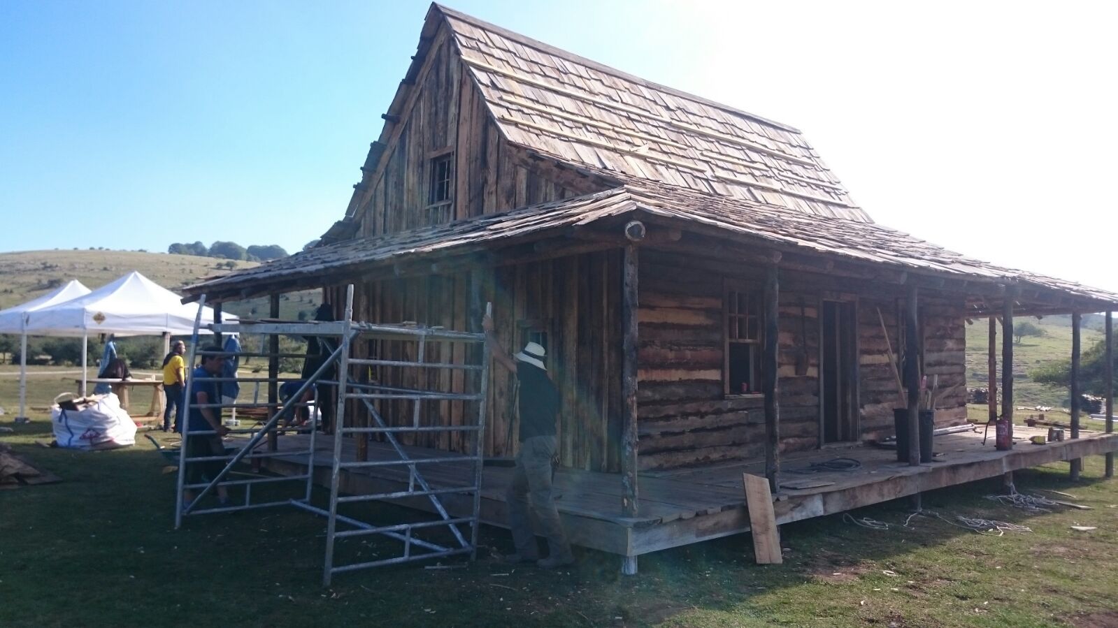 Se está construyendo una cabaña de troncos con porche en un campo.