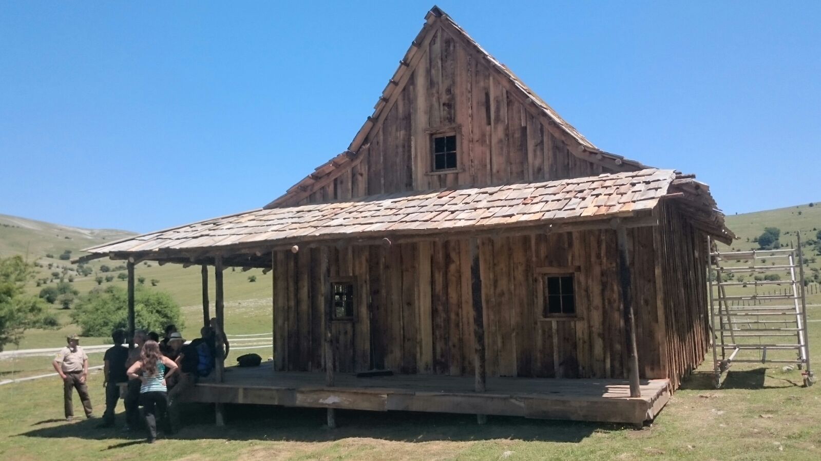 Un grupo de personas de pie frente a una casa de madera.