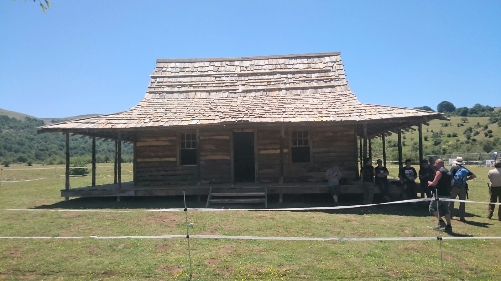 Un grupo de personas de pie frente a una casa de madera.