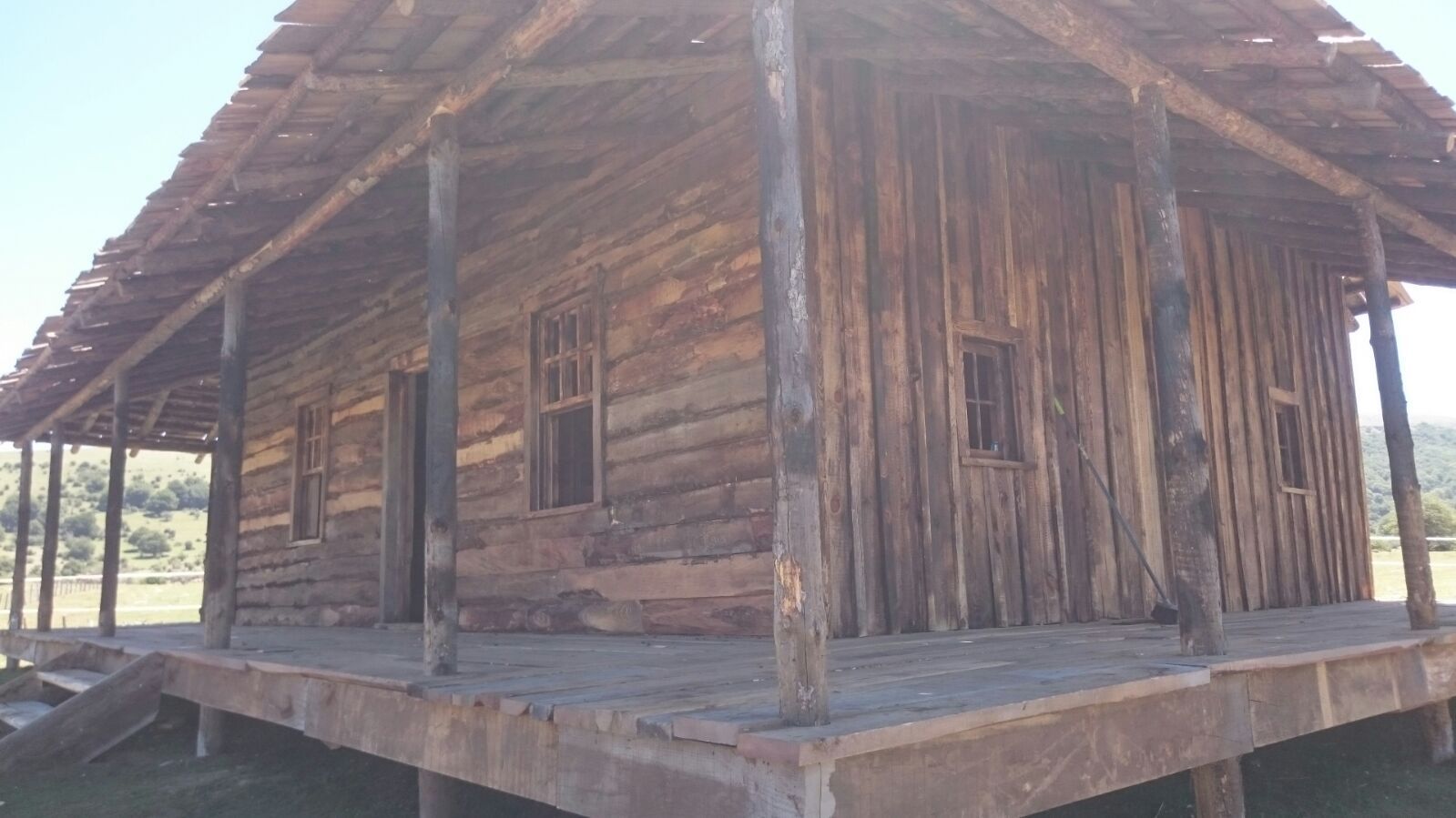 Una pequeña casa de madera con porche y techo.