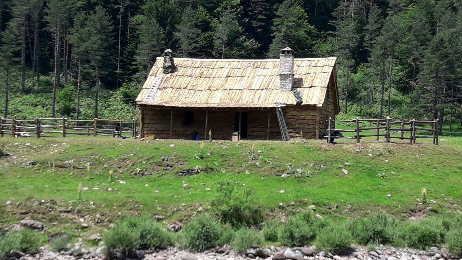 Una pequeña casa de madera está situada en medio de un campo de hierba.