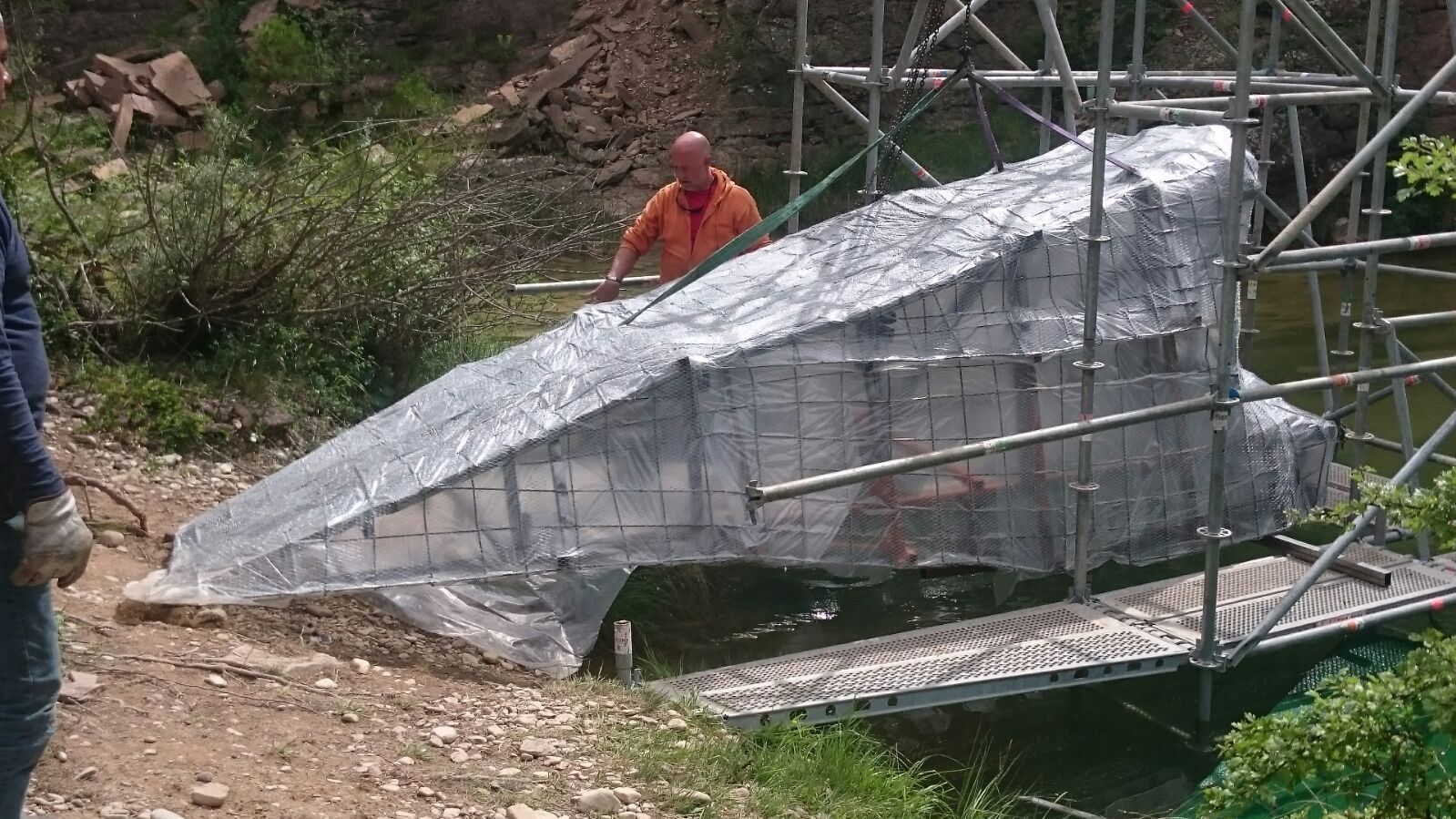 Un hombre está de pie junto a un gran trozo de metal envuelto en plástico.