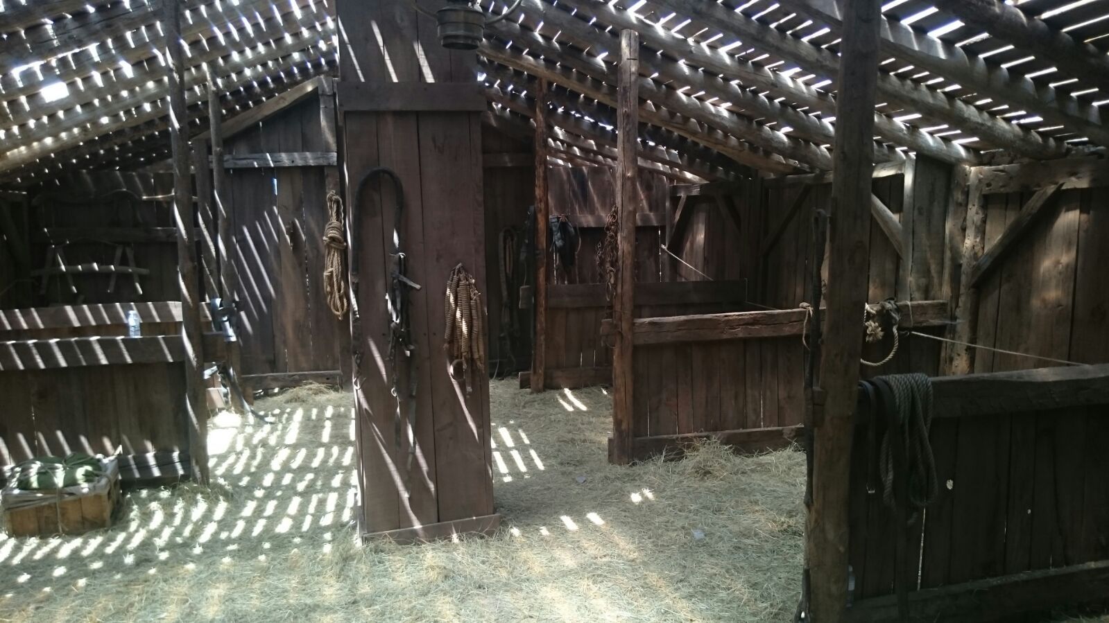 El interior de un granero de madera con heno en el suelo.