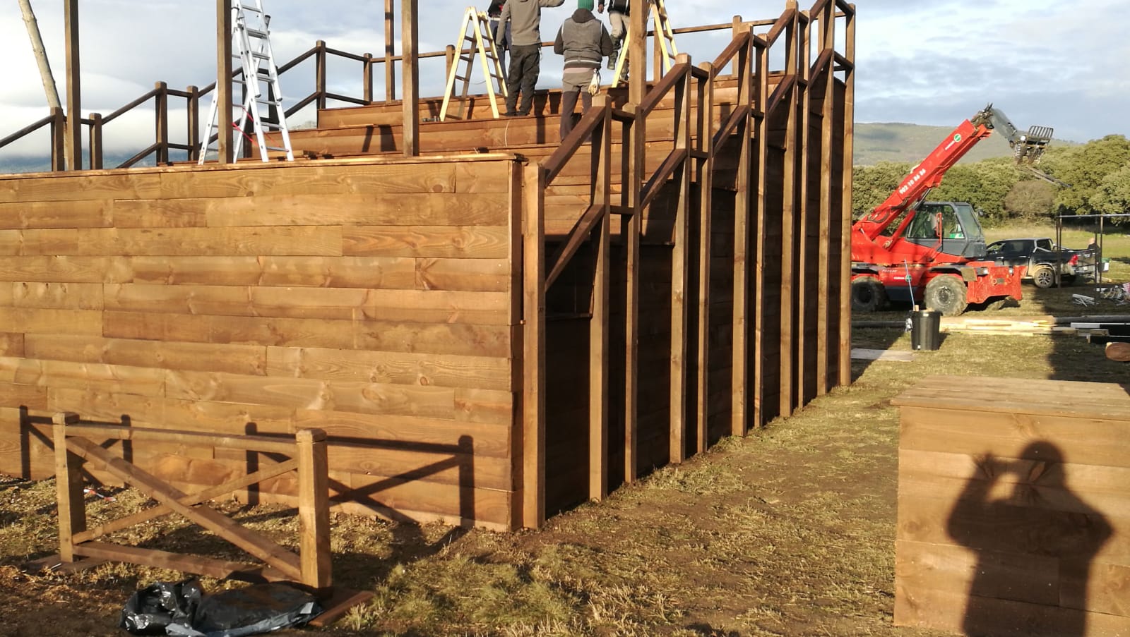 Un hombre está tomando una fotografía de una estructura de madera que se está construyendo.