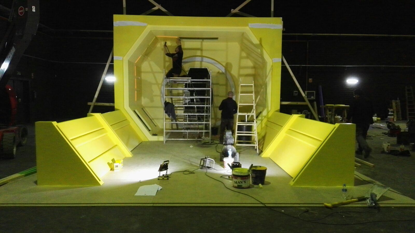 Un grupo de personas está trabajando en una gran estructura amarilla por la noche.