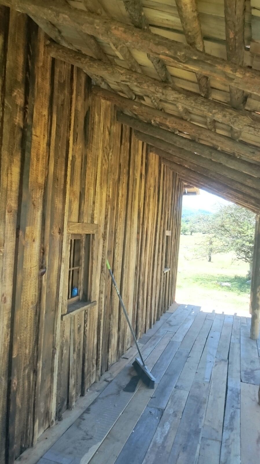 Un edificio de madera con una ventana y una escoba en el suelo.