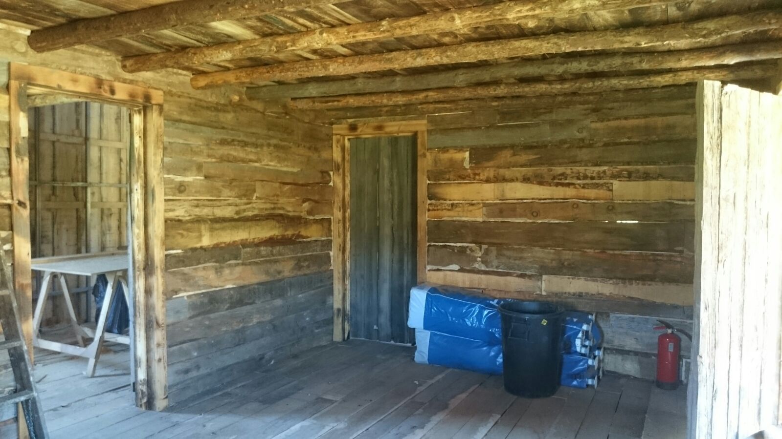 Una habitación de madera con un barril y un extintor dentro.