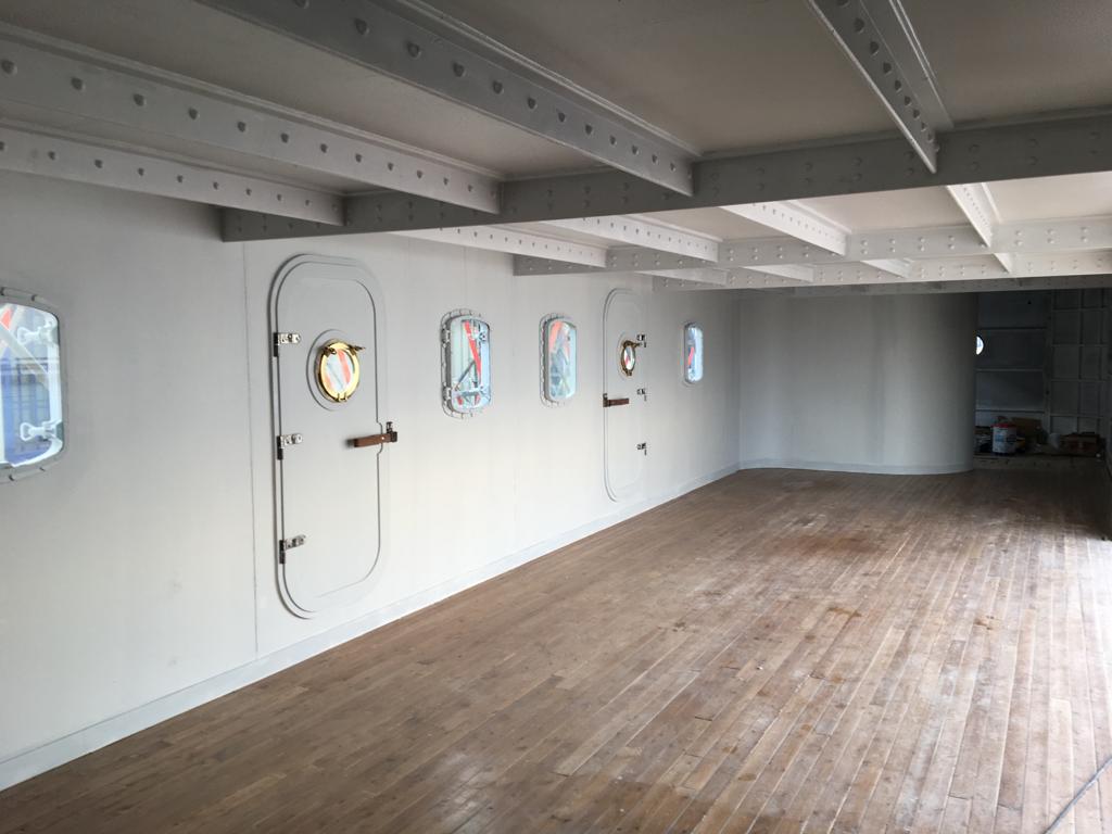 Una gran habitación vacía con suelos de madera y paredes blancas.