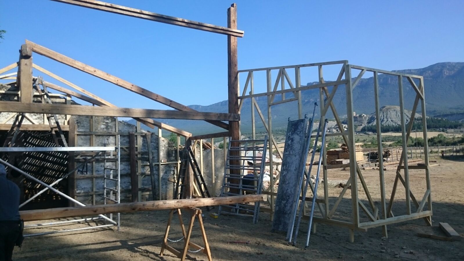 Se está construyendo una estructura de madera con montañas al fondo.