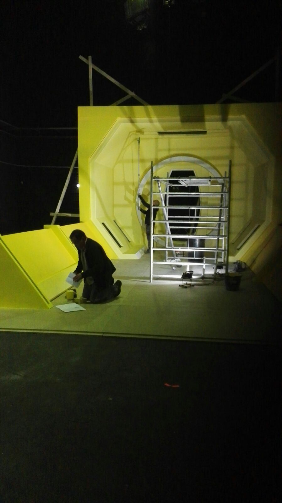 Un hombre está arrodillado frente a una pared amarilla.