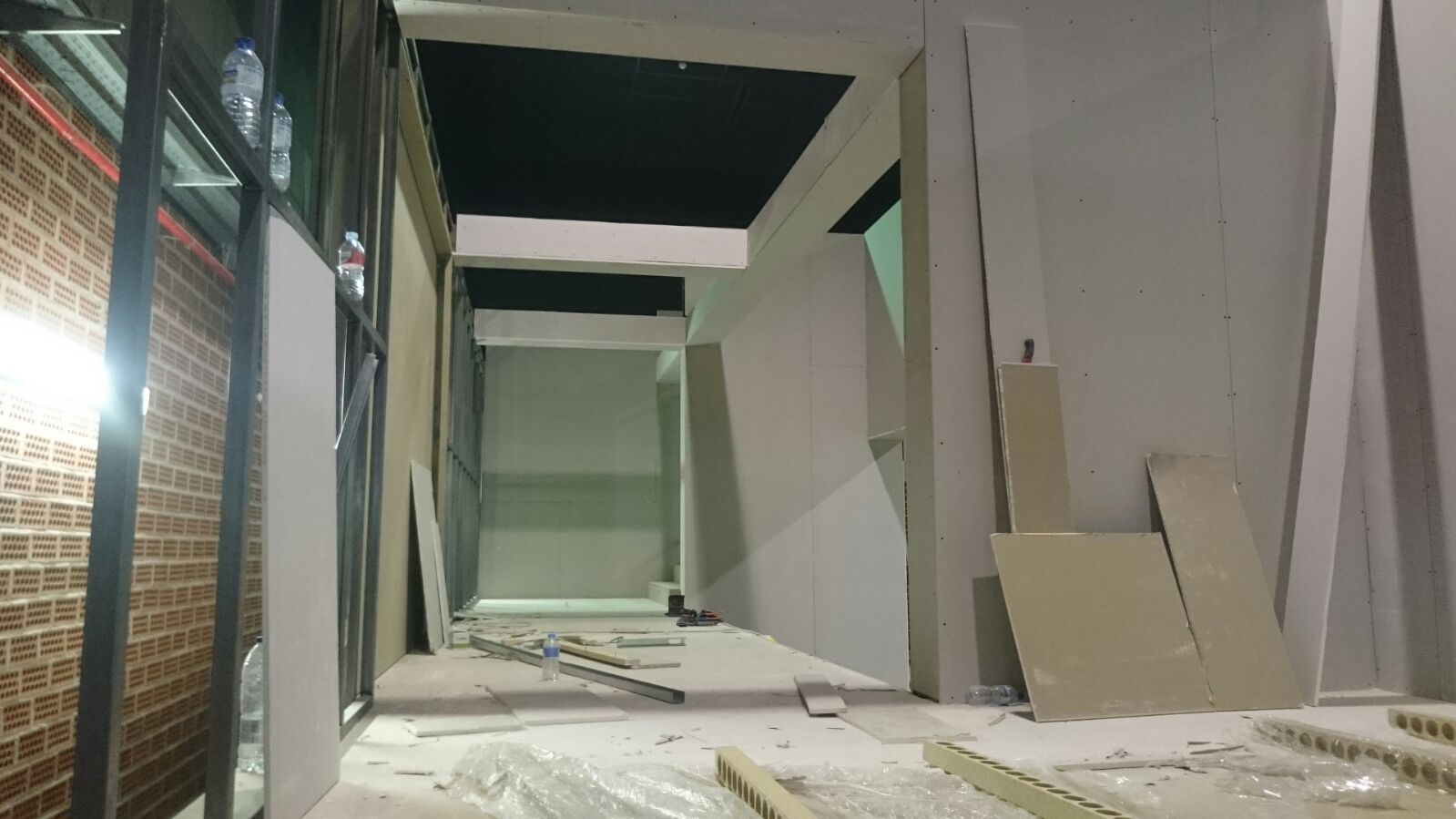 Un pasillo en un edificio en construcción con paredes de ladrillo y techo negro.