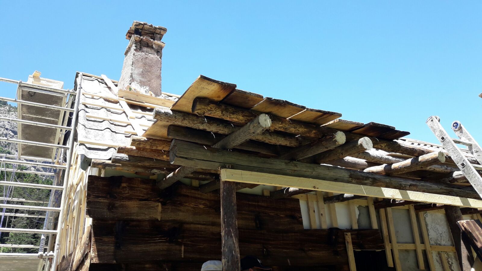 Una casa de madera con una chimenea en el tejado y una escalera delante de ella.