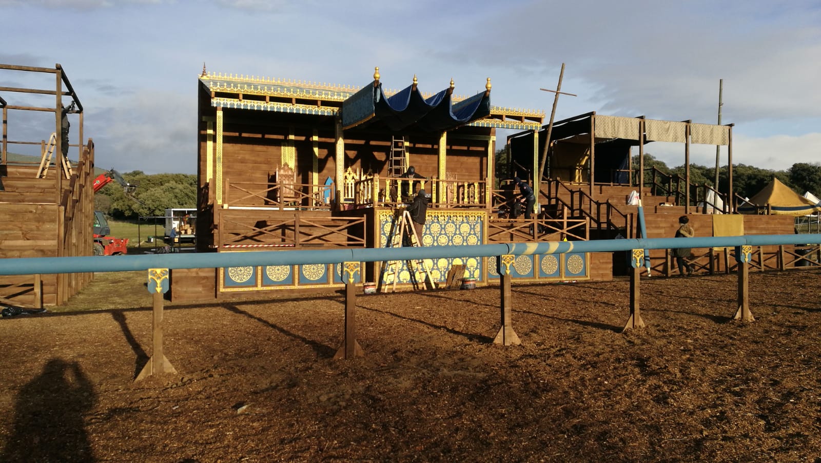 Un gran edificio de madera con una valla azul delante.
