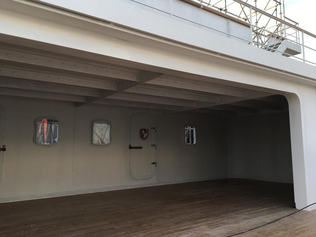 Una gran habitación vacía con una puerta y ventanas.