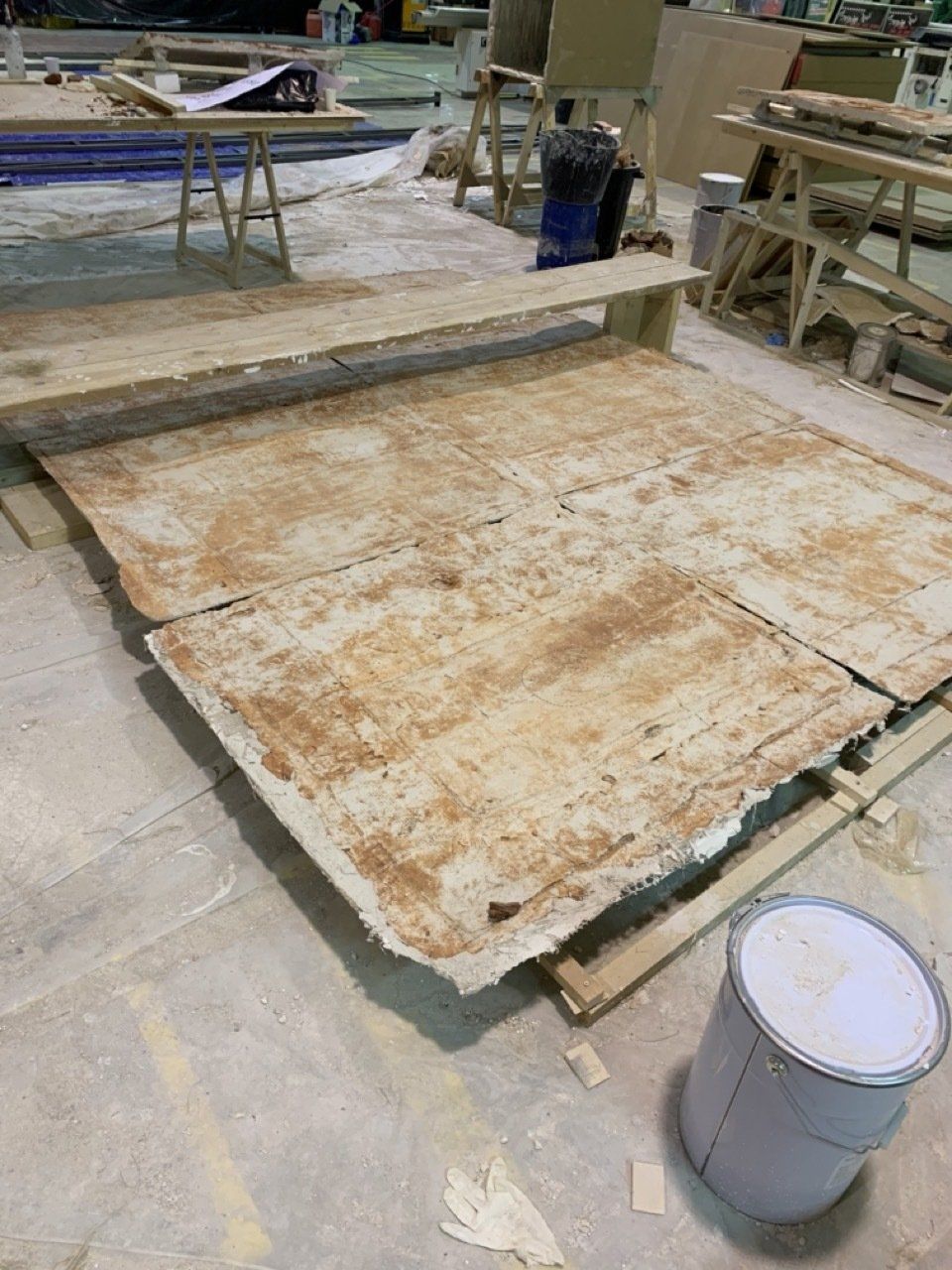 Un balde de pintura está en el suelo al lado de un gran trozo de madera.