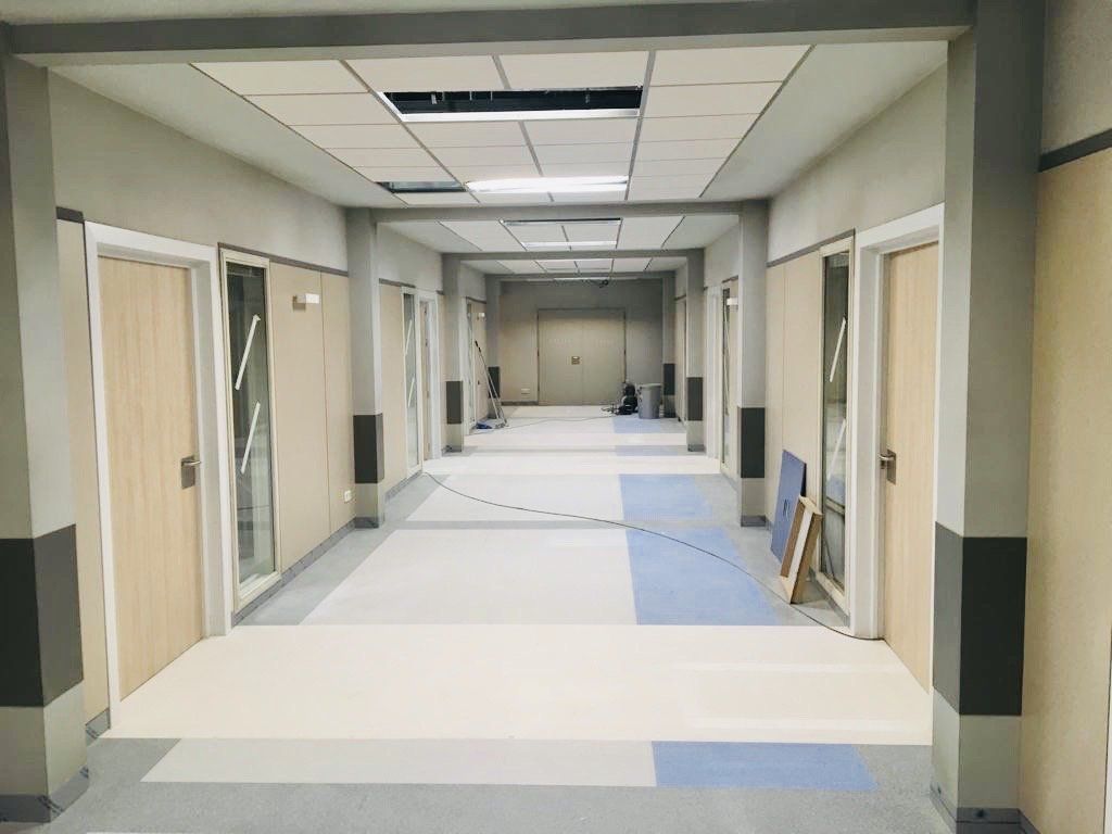 Un largo pasillo en un hospital con muchas puertas.