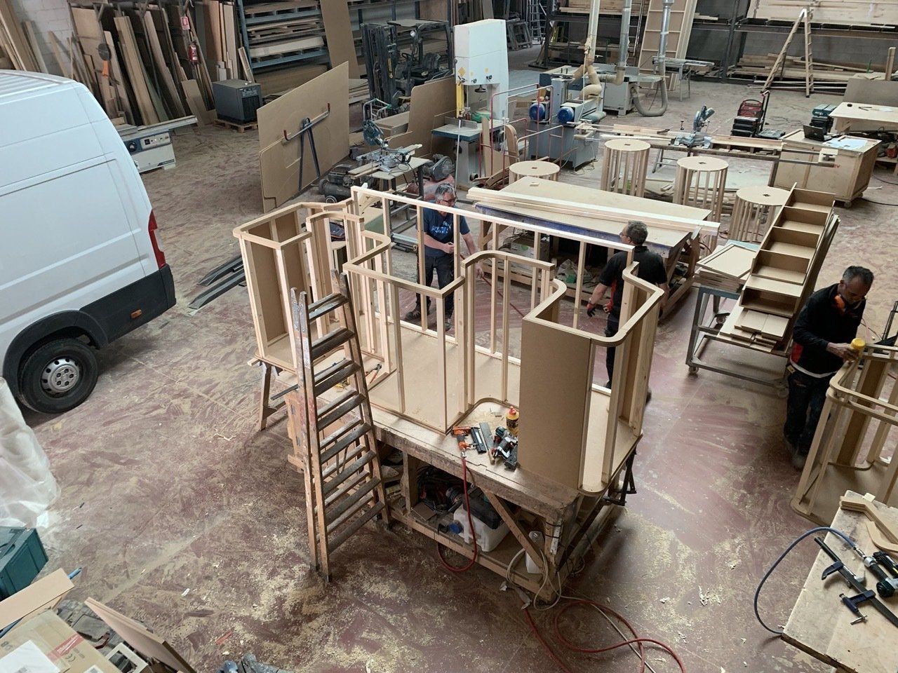Un grupo de personas está trabajando en una estructura de madera en una fábrica.