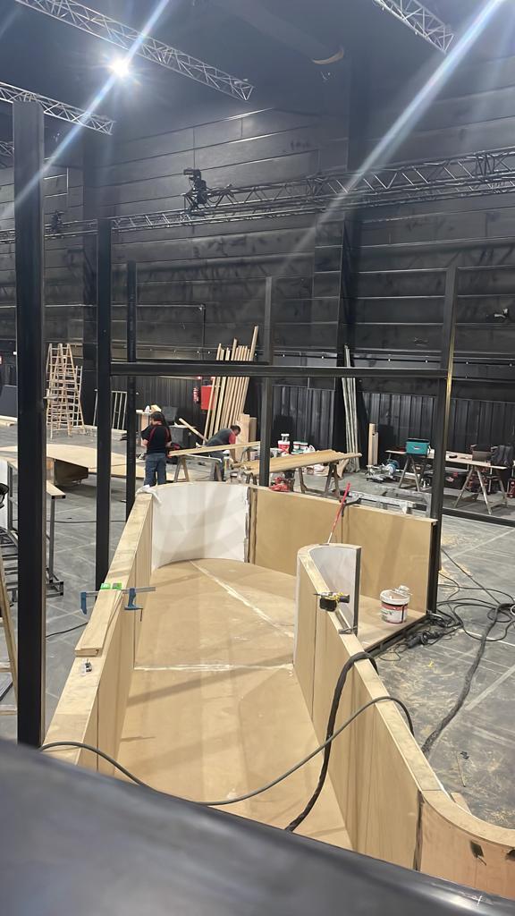 Un hombre está trabajando en una estructura de madera en un edificio grande.