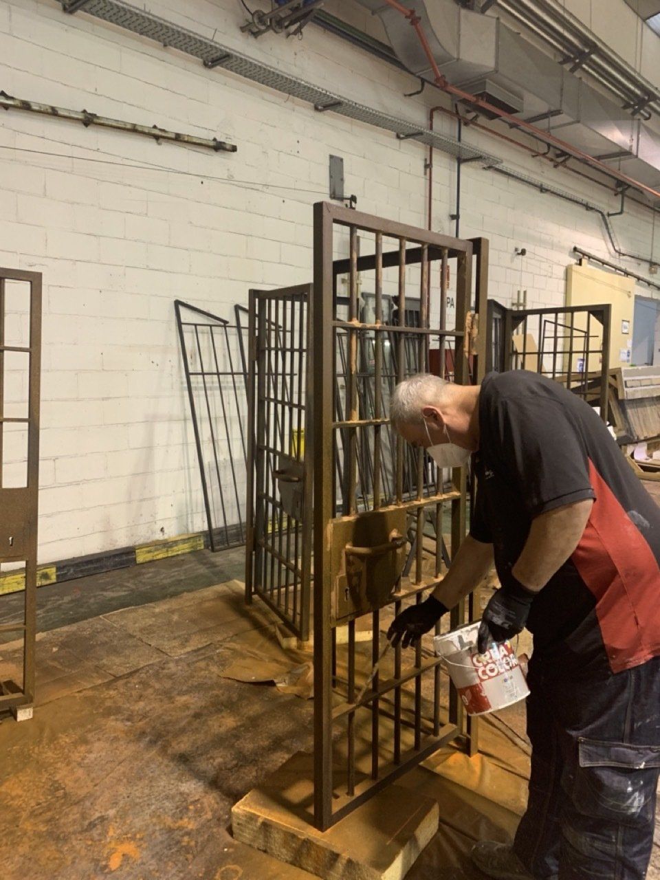 Un hombre está pintando una puerta de metal en una fábrica.
