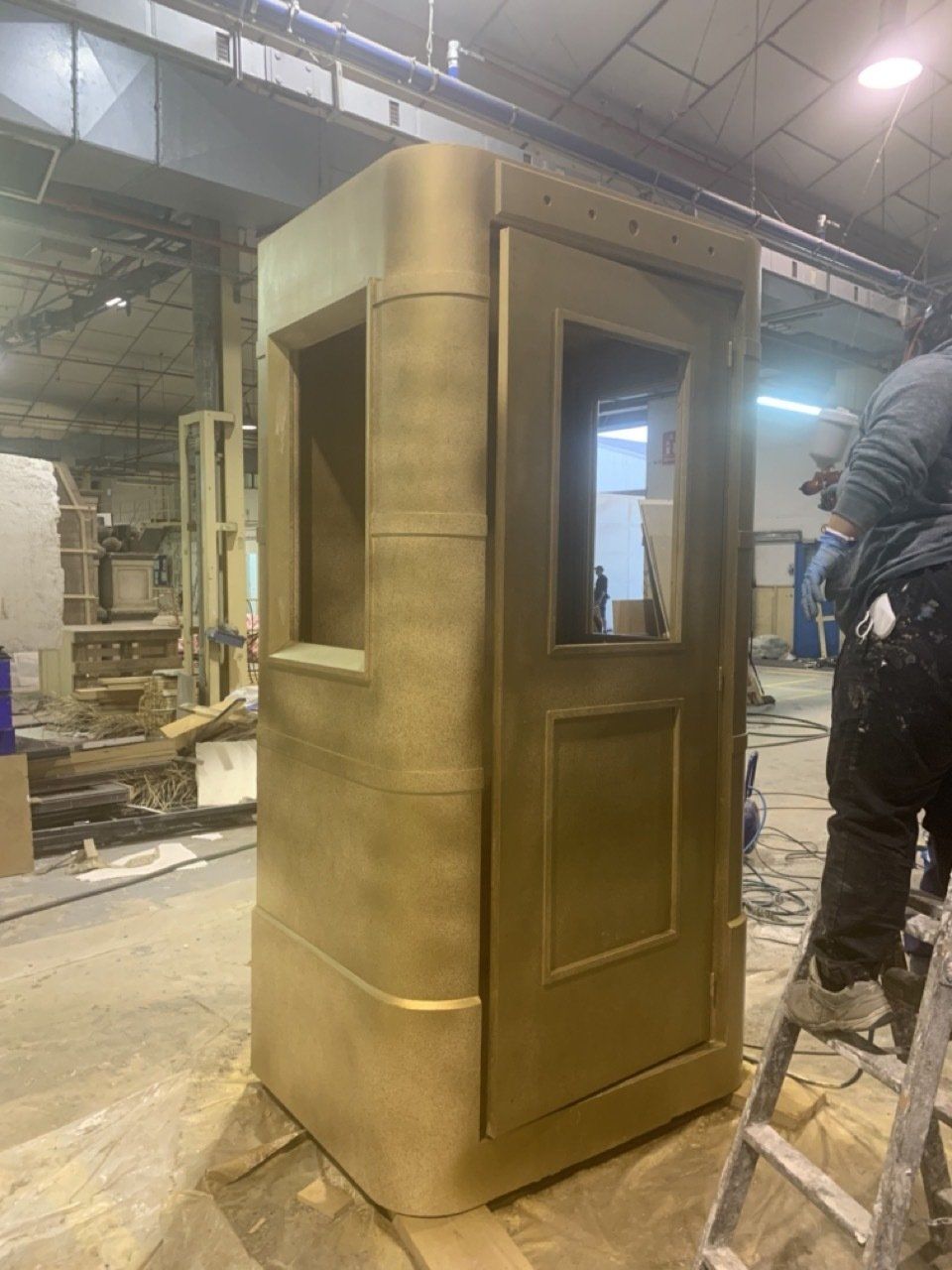 Un hombre está pintando una caja de oro en una fábrica.