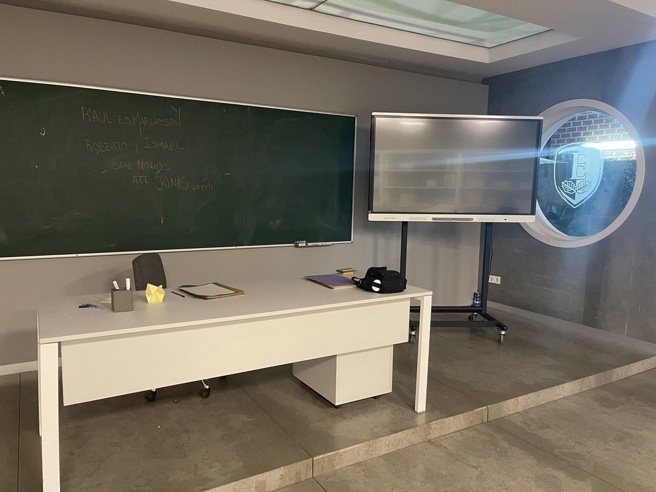 Un aula vacía con un escritorio y una pizarra.