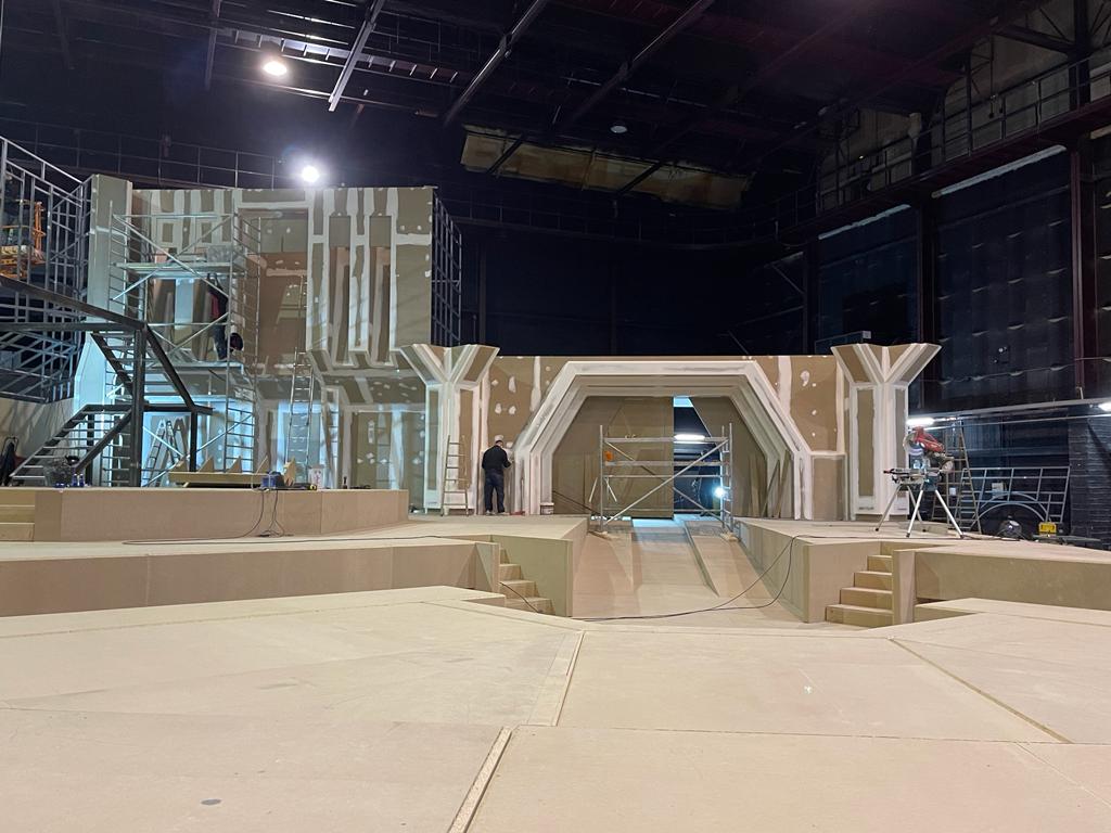 Se está construyendo un escenario en un gran edificio por la noche.