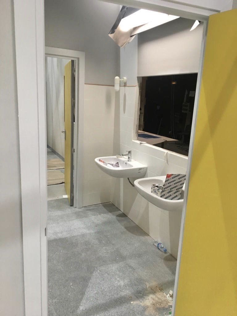 Un baño con dos lavabos y una puerta amarilla.