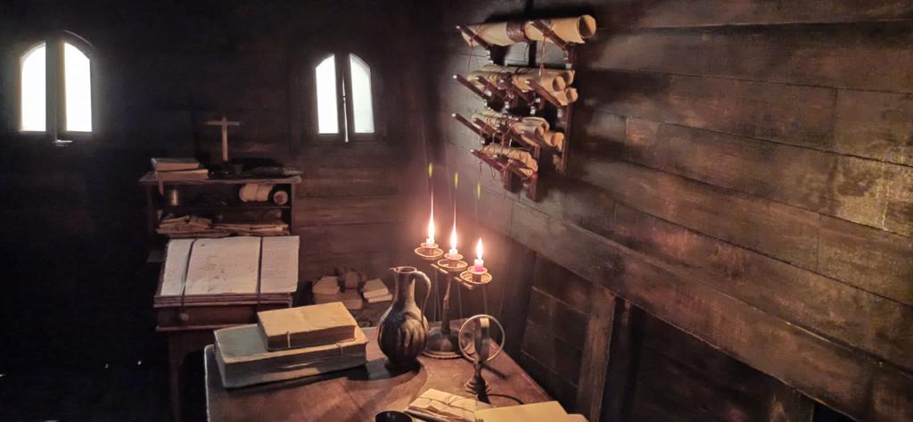 Una habitación de madera con velas en una mesa y una cruz en la pared.