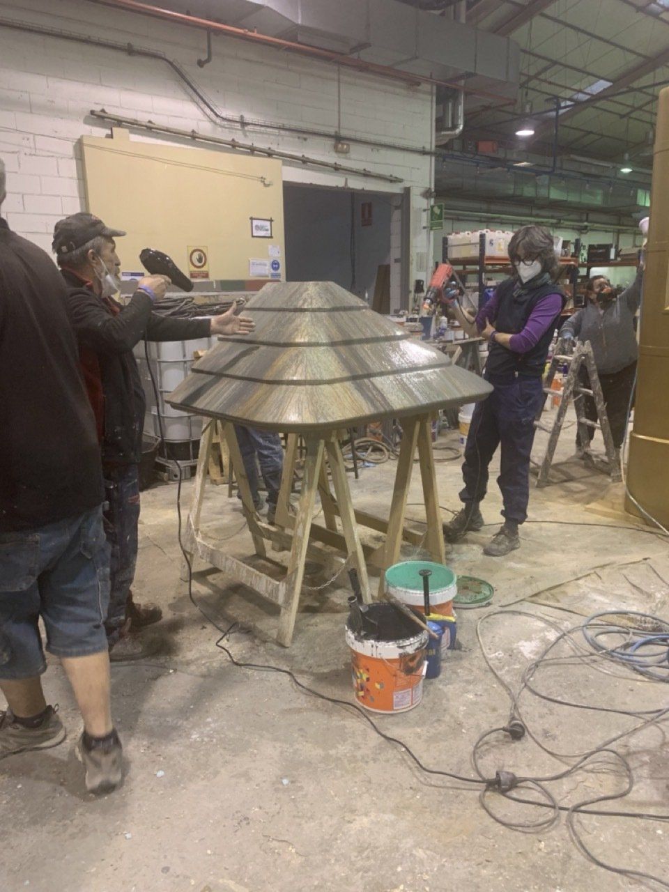 Un grupo de personas está trabajando en una pieza de metal en una fábrica.
