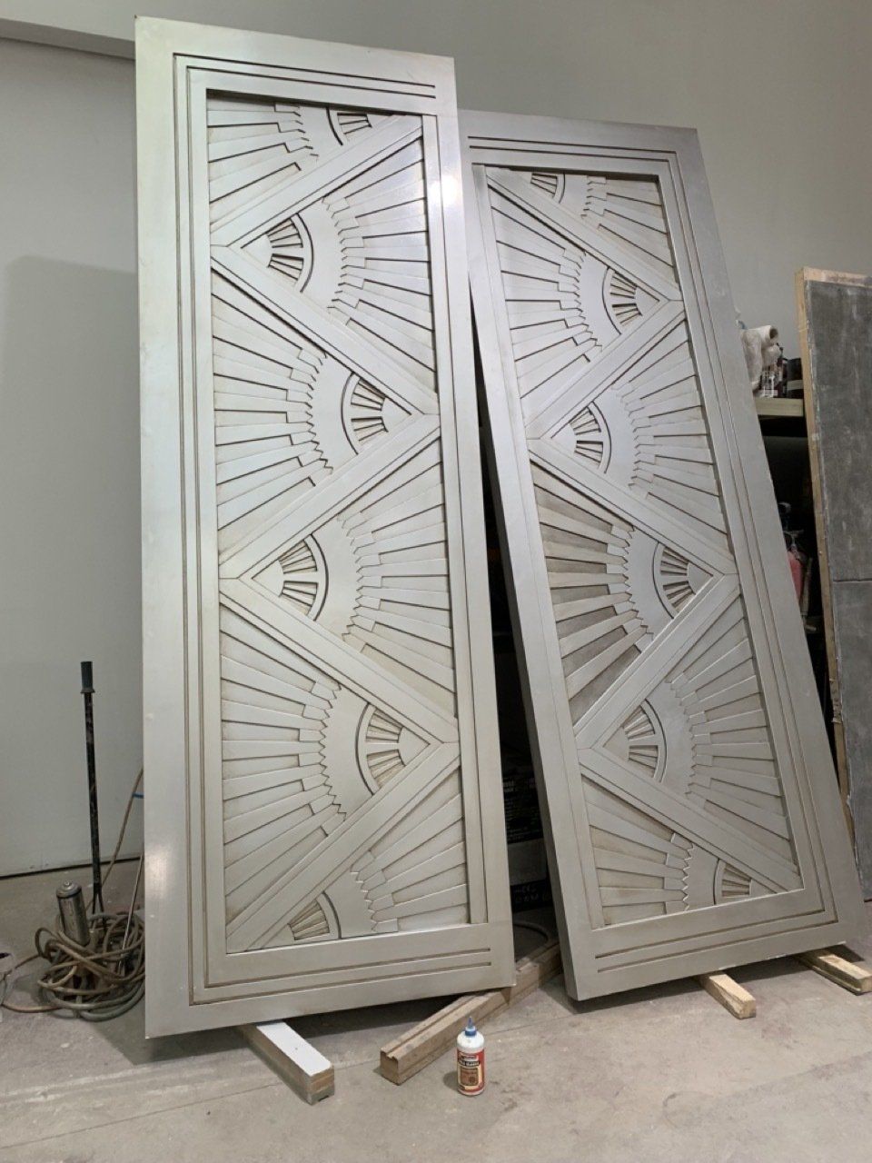 Dos puertas blancas con un diseño geométrico se encuentran sobre un piso de madera.