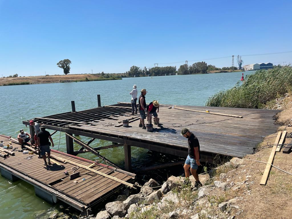 Un grupo de personas está trabajando en un muelle al lado de un cuerpo de agua.