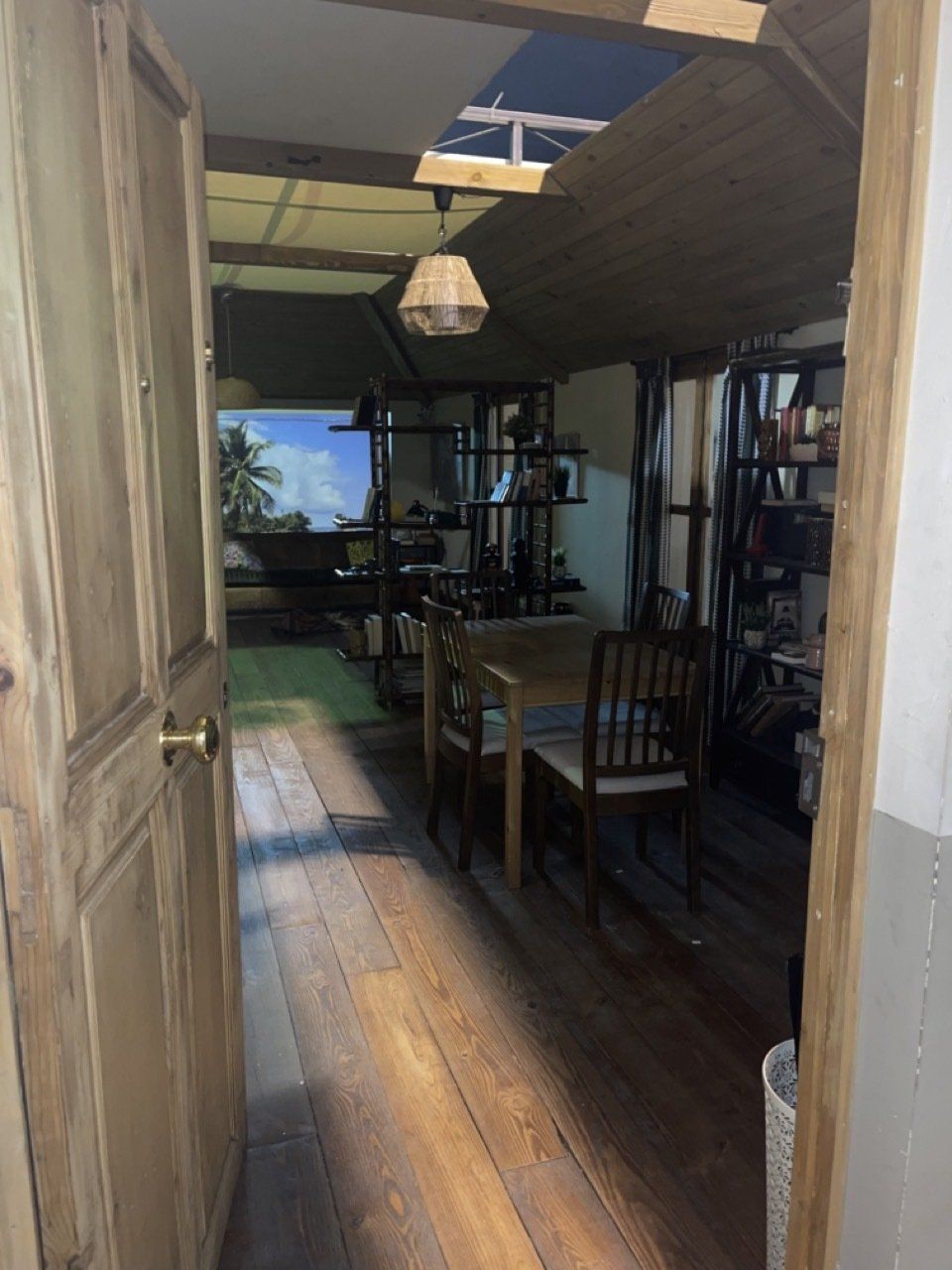 Un pasillo con suelo de madera y una mesa y sillas.